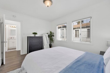 Bright modern bedroom interior inside one of the luxury vacation rentals West Los Angeles with large windows looking onto the driveway.