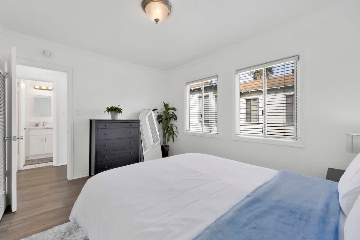 Bright modern bedroom interior inside one of the luxury vacation rentals West Los Angeles with large windows looking onto the driveway.